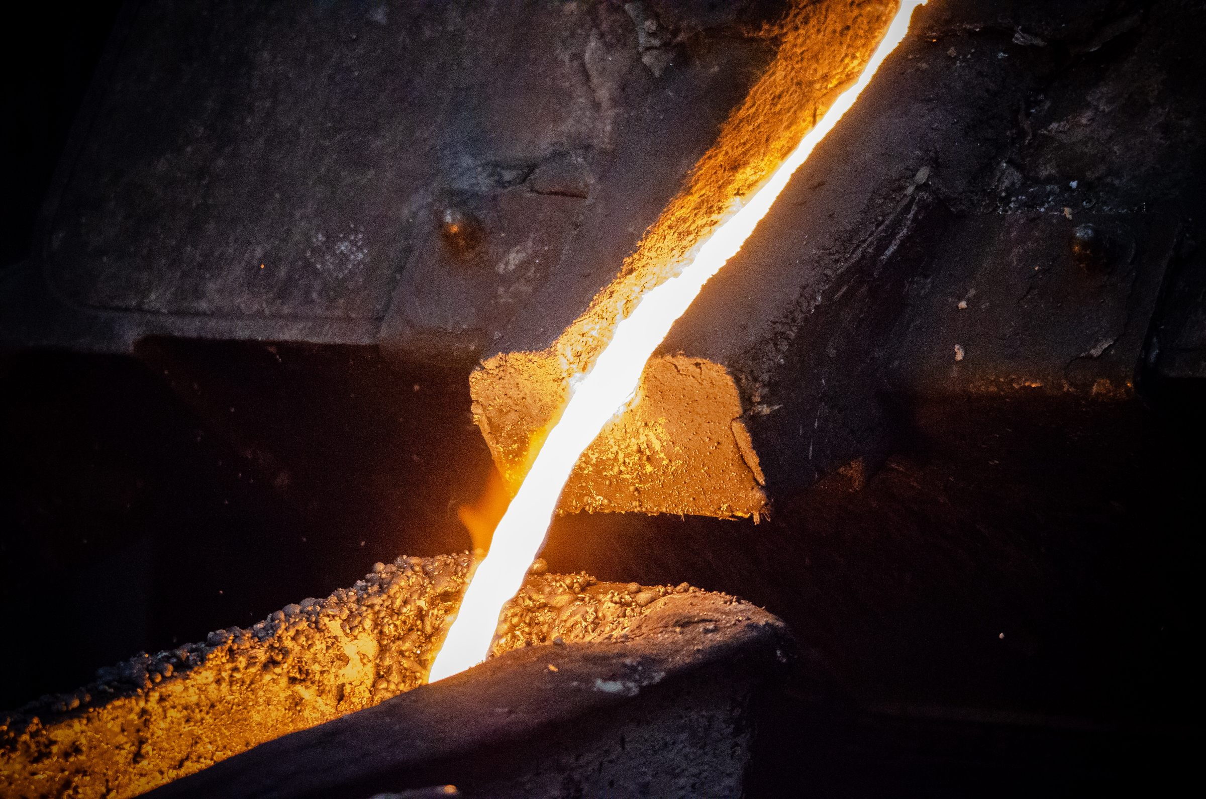 Close-up of molten metal flowing through industrial furnace equipment