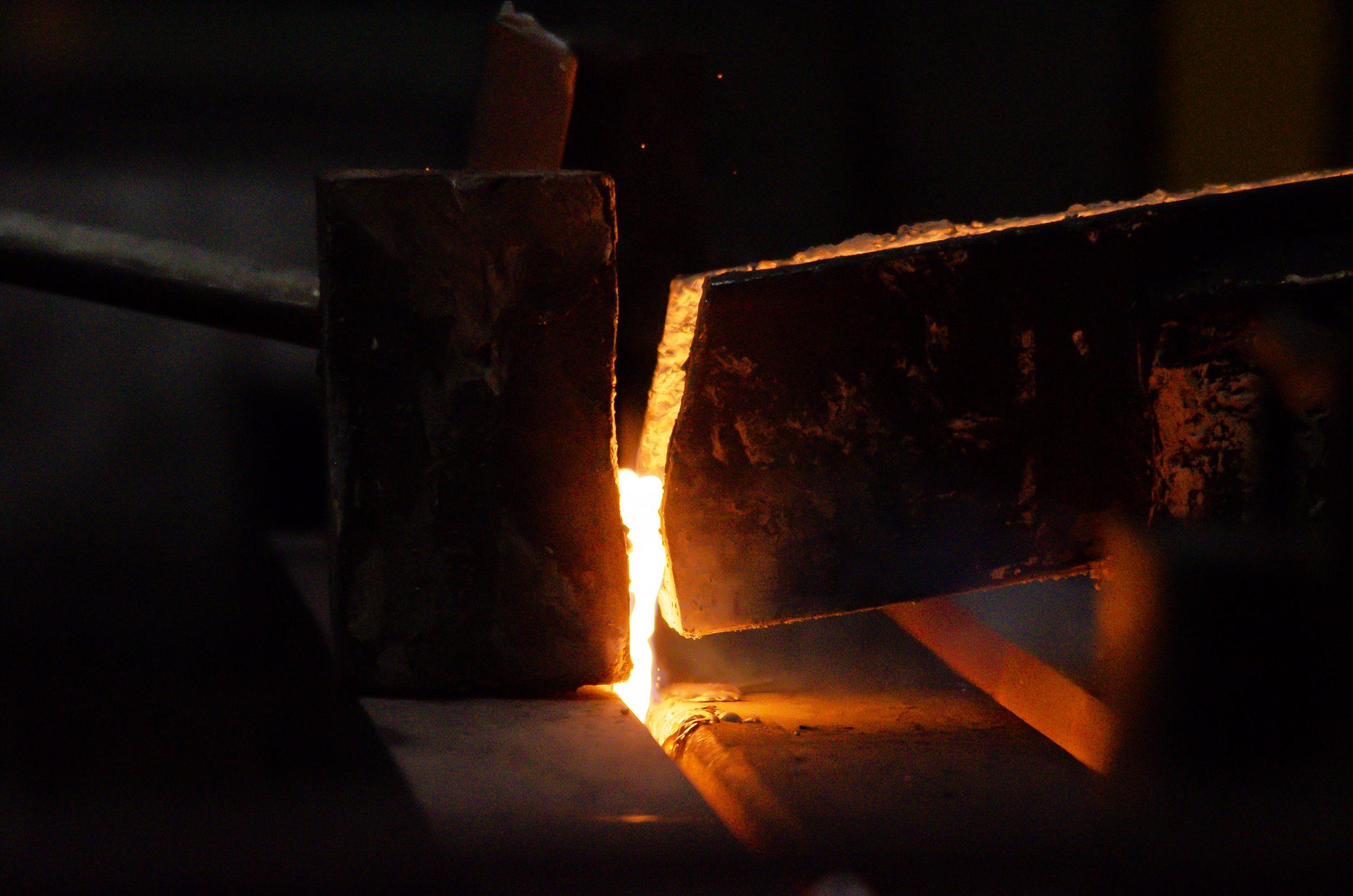 Industrial furnace tooling surrounding a bright stream of molten metal
