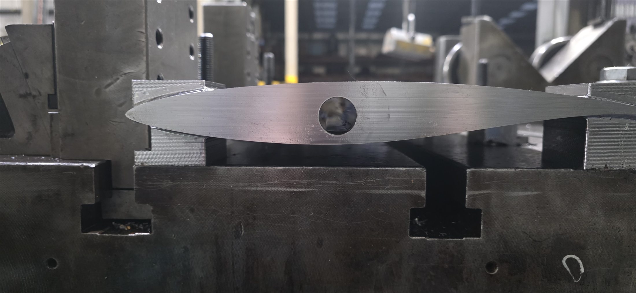 Profiled metal component with a precision through-bore in a machining fixture